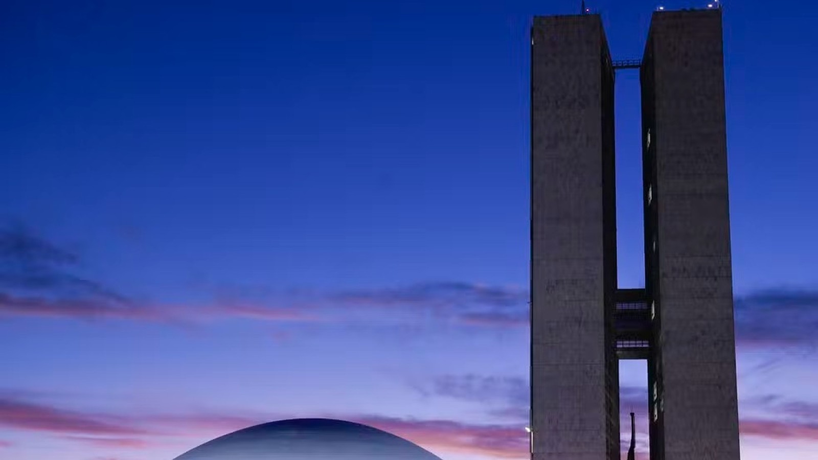 Congresso Nacional em Brasília com torres e cúpula, céu azul e roxo ao entardecer
