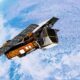Conceito artístico de um satélite com painéis solares orbitando o planeta Terra, texto 'Artist's concept'