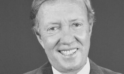 Retrato em preto e branco de Roberto Maya, homem sorridente com terno e camisa branca