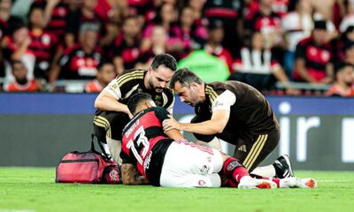 Jogador Danilo (camisa 13) deitado no gramado, atendido por dois médicos em campo de futebol