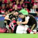 Jogador Danilo (camisa 13) deitado no gramado, atendido por dois médicos em campo de futebol