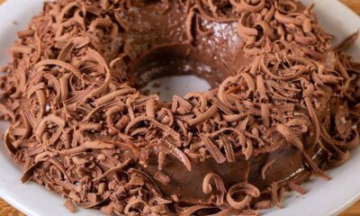 Brigadeirão de chocolate em forma de anel coberto com raspas de chocolate em um prato branco