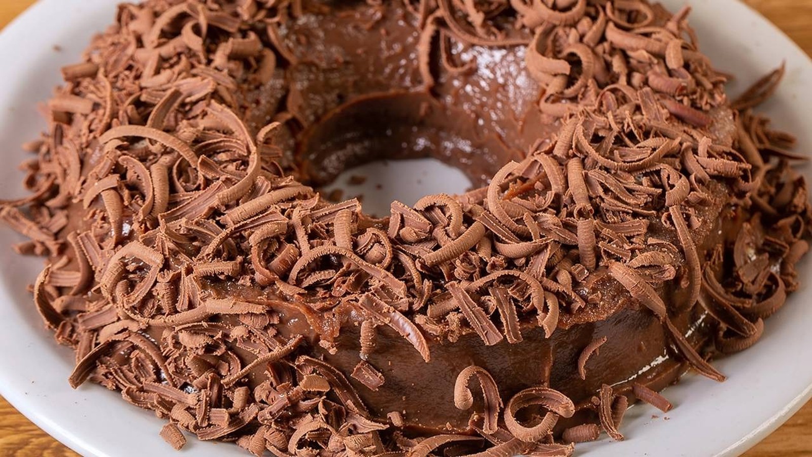 Brigadeirão de chocolate em forma de anel coberto com raspas de chocolate em um prato branco