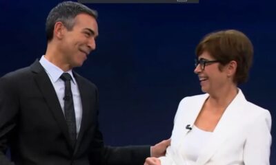 César Tralli e Renata Vasconcellos sorrindo um para o outro em estúdio de TV