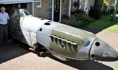 Peter Arnold ao lado da fuselagem de um caça Spitfire dentro de uma garagem