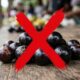 Frutas escuras e redondas em mesa de madeira rústica com um grande 'X' vermelho sobre elas