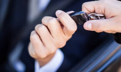 Duas mãos seguram um chaveiro de carro preto com a palavra 'UNLOCK' visível