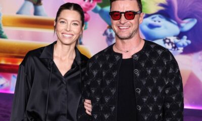 Jessica Biel e Justin Timberlake sorrindo, ele de óculos vermelhos e jaqueta preta acolchoada