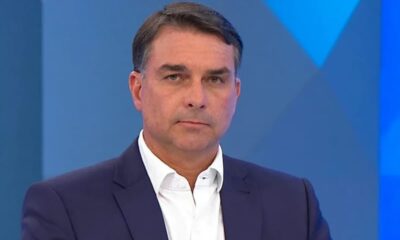 Homem branco, Flávio Bolsonaro, em terno azul marinho e camisa branca, olhar sério