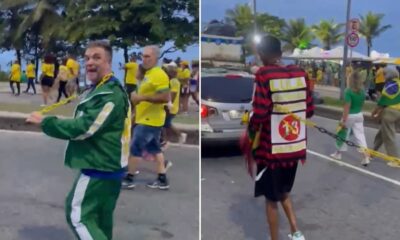 Homem em agasalho verde puxa corrente presa a outro homem com camisa "LULA 13" nas costas