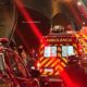 Ambulância vermelha e carros de bombeiros com luzes piscando em local de acidente à noite