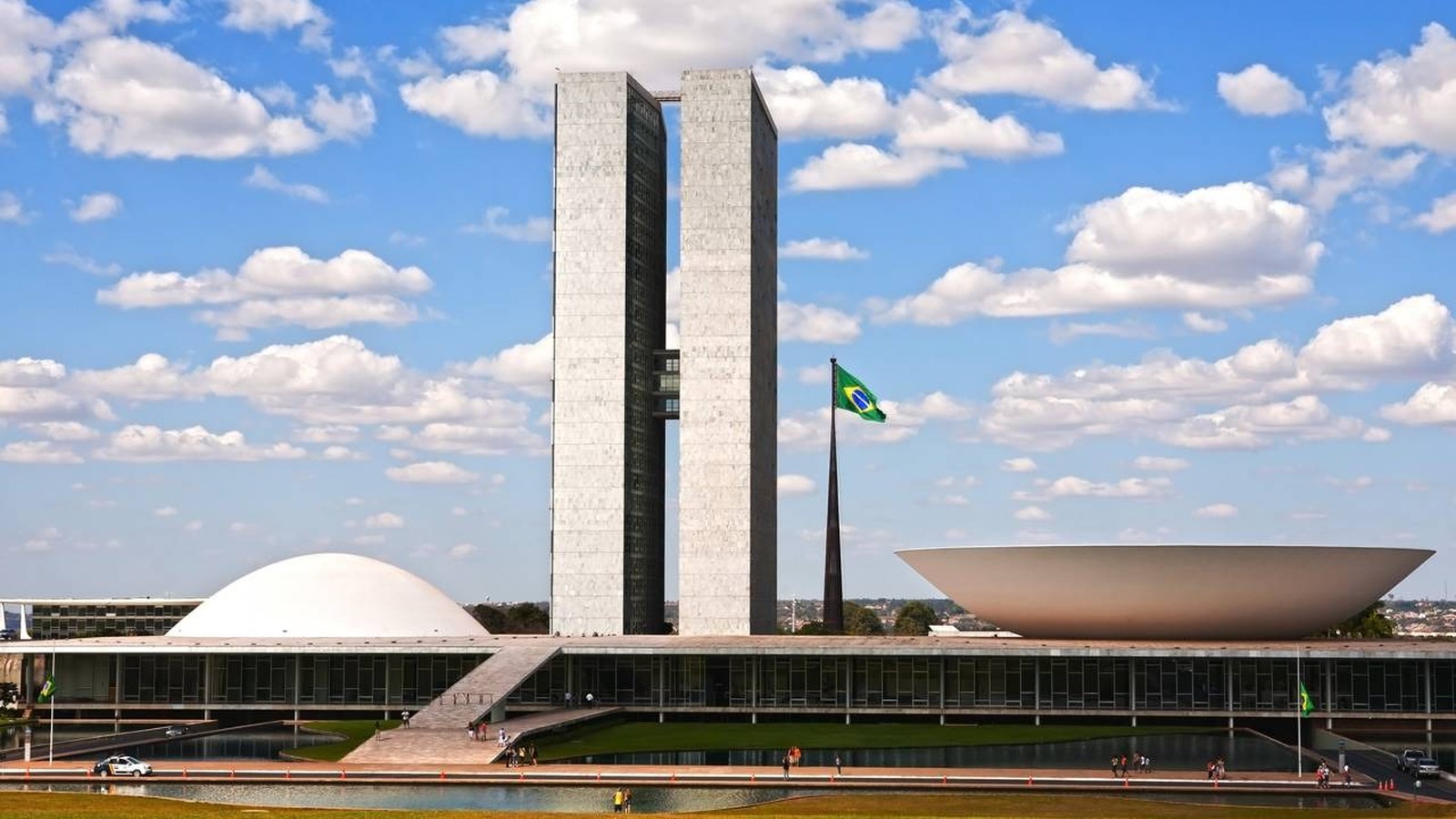 Congresso Nacional do Brasil: duas torres, cúpula, tigela, bandeira brasileira, céu azul