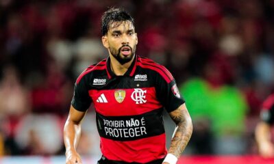 Jogador Lucas Paquetá veste camisa vermelha e preta do Flamengo, olhando focado no campo