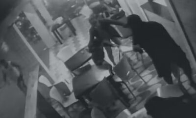 Pessoa arrastando outra no chão em lanchonete durante tiroteio, capturado por câmera de segurança
