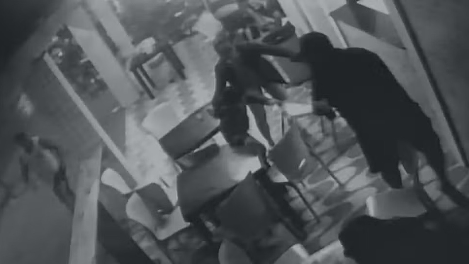 Pessoa arrastando outra no chão em lanchonete durante tiroteio, capturado por câmera de segurança