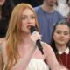 Marina Ruy Barbosa, ruiva, em close, segura microfone preto e fala durante programa de TV
