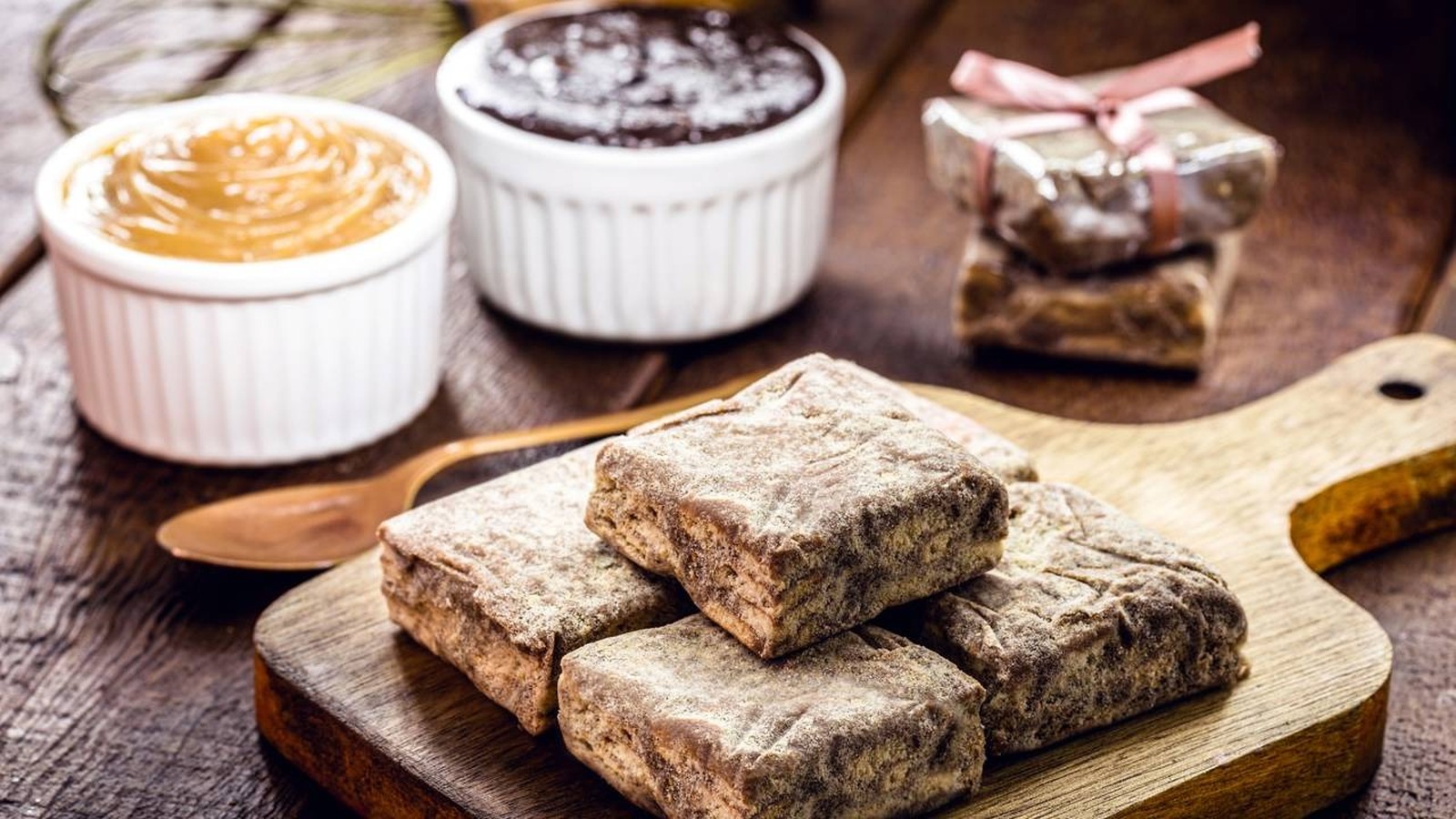 Palha italiana com açúcar em tábua, potes de brigadeiro e doce de leite