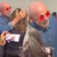 Lula, de óculos estrela, abraça mulher, pessoas filmam. Em segundo plano, camisa com "L"