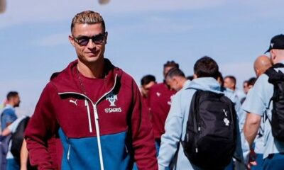Cristiano Ronaldo com jaqueta Puma vinho e azul, logo Sagres, óculos de sol, sorrindo