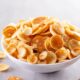 Tigela branca cheia de mini panquecas douradas e redondas sobre uma superfície cinza claro
