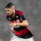 Homem barbudo com camisa do Flamengo, vermelho e preta, correndo sob chuva