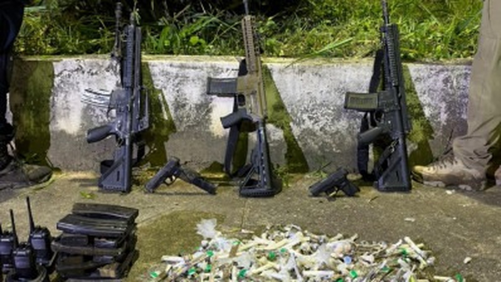 Três fuzis, duas pistolas, carregadores, rádios e drogas embaladas no chão