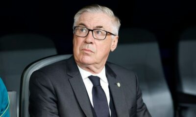 Homem de meia-idade com óculos, cabelo grisalho, terno escuro e gravata, olhando pensativo