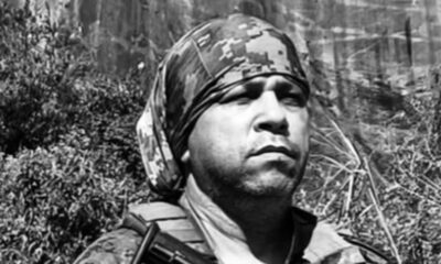 Retrato de homem em preto e branco com bandana camuflada e colete tático