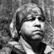 Retrato de homem em preto e branco com bandana camuflada e colete tático