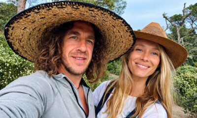 Carles Puyol e Vanesa Lorenzo sorrindo com chapéus de palha em meio à natureza