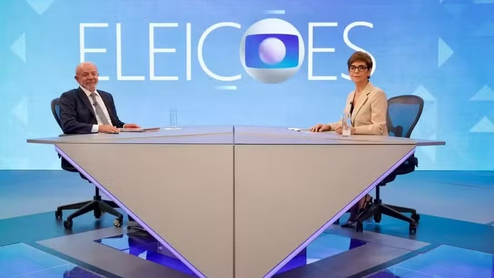 Lula e Renata Lo Prete em estúdio de TV, sentados em mesa, com a inscrição ELEICOES e logo Globo