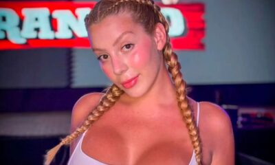 Mulher loira com duas tranças, blush visível, sorrindo em primeiro plano