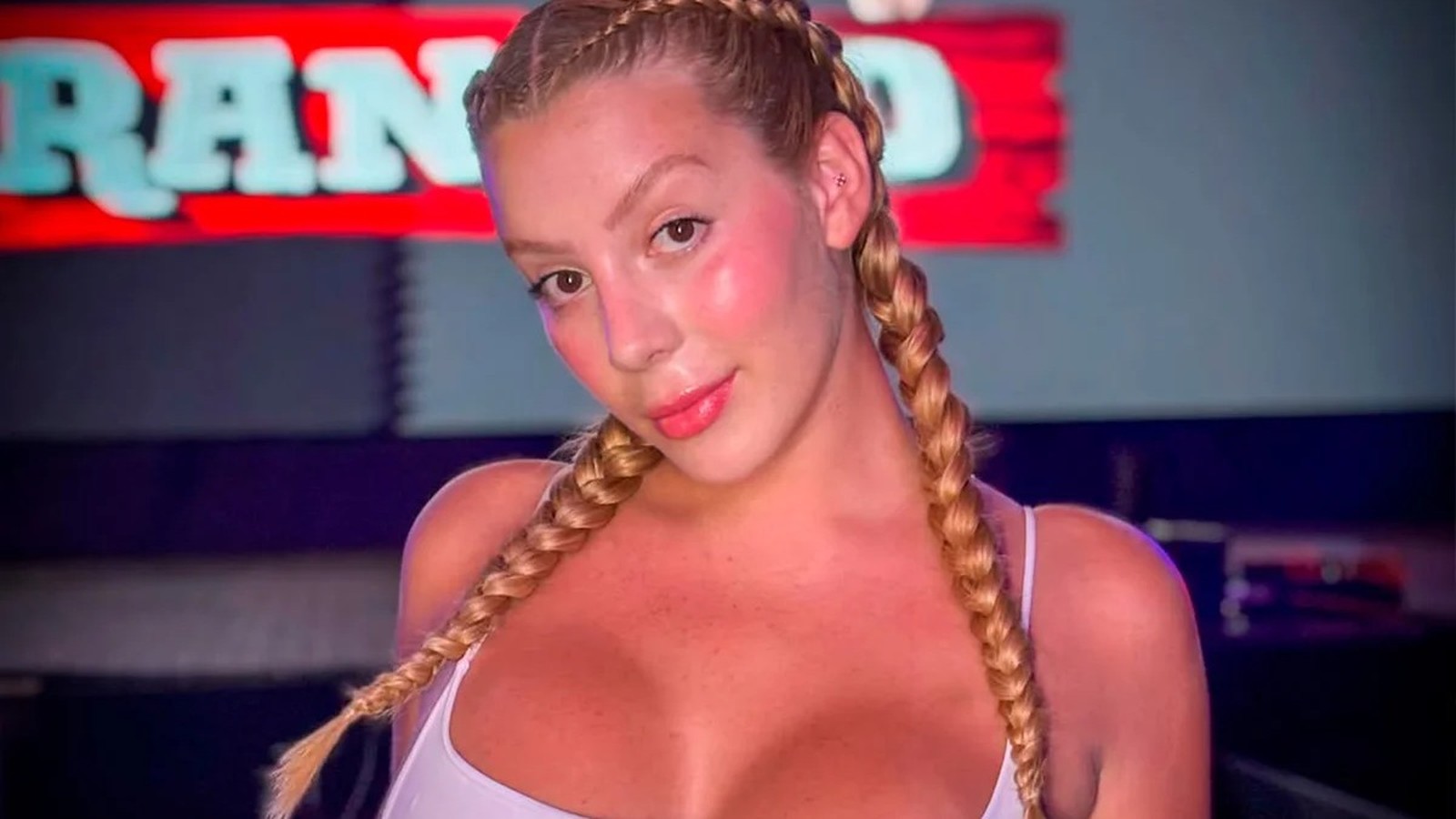 Mulher loira com duas tranças, blush visível, sorrindo em primeiro plano