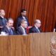 Ministros do Tribunal Superior Eleitoral, alguns sentados, alguns em pé, em sala de audiências formal