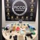 Mesa com drogas, dinheiro, pistola, munições e celulares apreendidos, com banner da FICCO Roraima