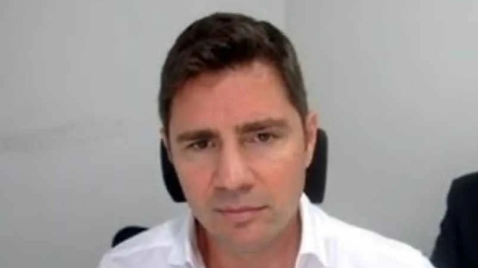 Rosto de homem, cabelos escuros, camisa branca, olhando diretamente para a câmera