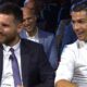 Lionel Messi e Cristiano Ronaldo sorrindo e sentados um ao lado do outro em evento