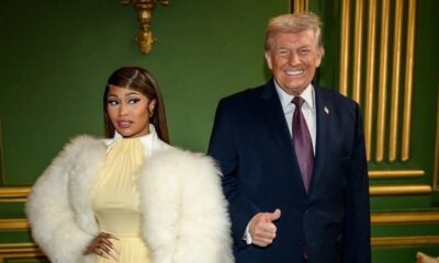 Nicki Minaj com casaco de pele branco e Donald Trump de terno e gravata, sorrindo, fazendo polegar para cima