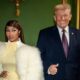 Nicki Minaj com casaco de pele branco e Donald Trump de terno e gravata, sorrindo, fazendo polegar para cima