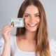 Mulher jovem sorridente segurando a nova Carteira de Identidade Nacional brasileira