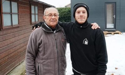 Homem idoso com óculos e homem jovem em quintal nevado, braços um sobre o outro