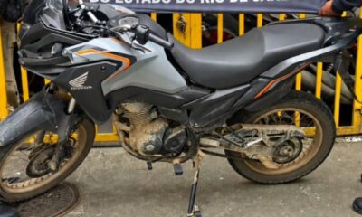 Motocicleta Honda XRE cinza e suja com detalhes em laranja, marca Honda visível