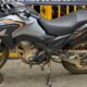 Motocicleta Honda XRE cinza e suja com detalhes em laranja, marca Honda visível