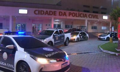 Viaturas da Polícia Civil com luzes acesas em frente à Cidade da Polícia à noite