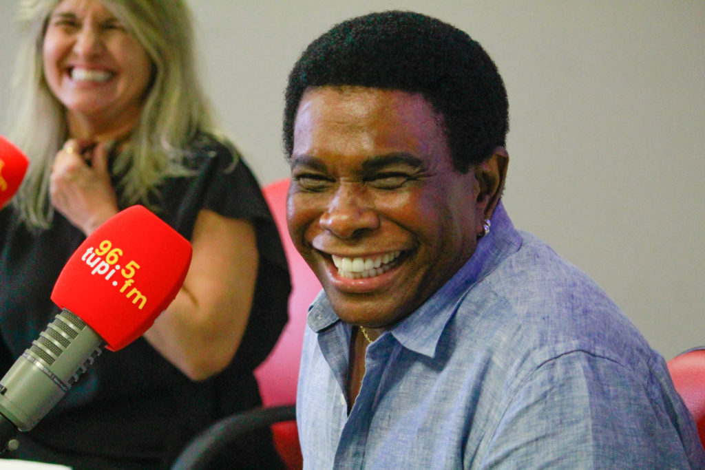 Neguinho da Beija-Flor sorrindo e Márcia Pinho ao fundo