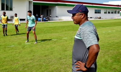 De boné roxo e camisa cinza, Roger Machado observa o treino do Fluminense