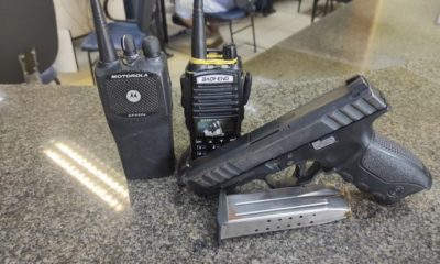 rádio de comunicação e arma em cima da mesa