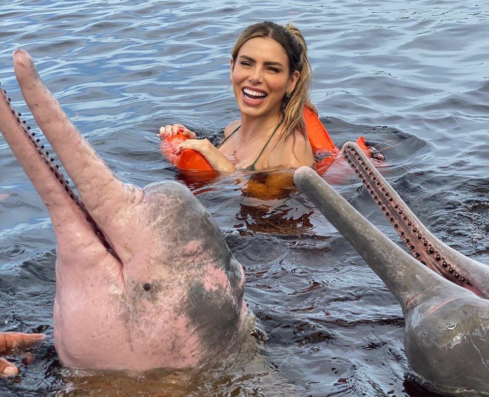 Erika Schneider nada com botos no Rio Negro (Divulgação)