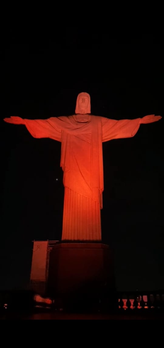Estátua do Cristo Redentor iluminado na cor laranja