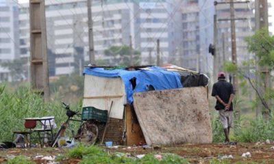morador de rua ao lado de uma barra de papelão